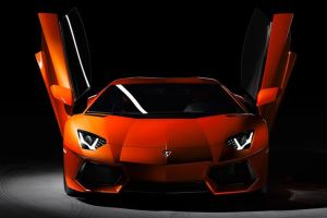 orange color Lamborghini Aventador with vertical doors open and headlights turned on